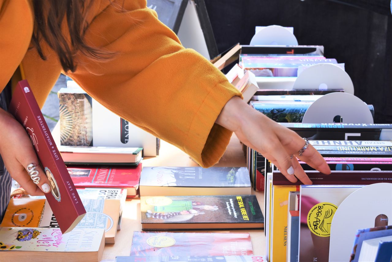 Hånd rækker ud efter bøger.