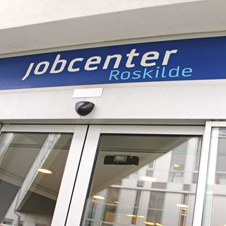 Jobcenter Roskildes indgangsparti med automatiske døre og et blåt skilt.