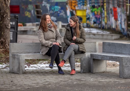 To kvinder sidder på betonbænk