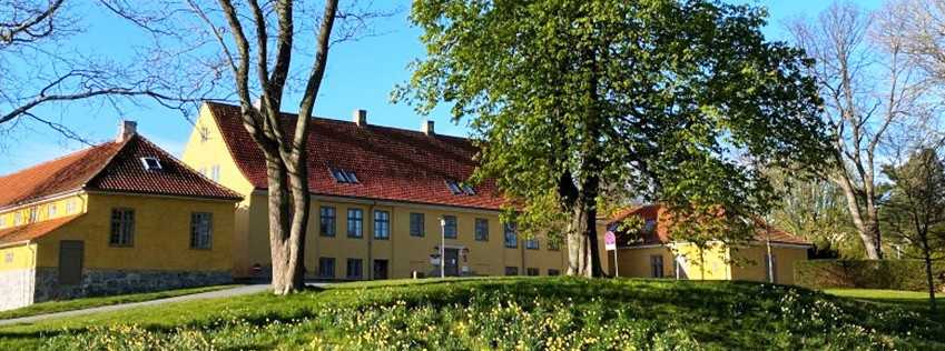 Gul bygning med rødt tag. Billedet er taget langt væk fra.