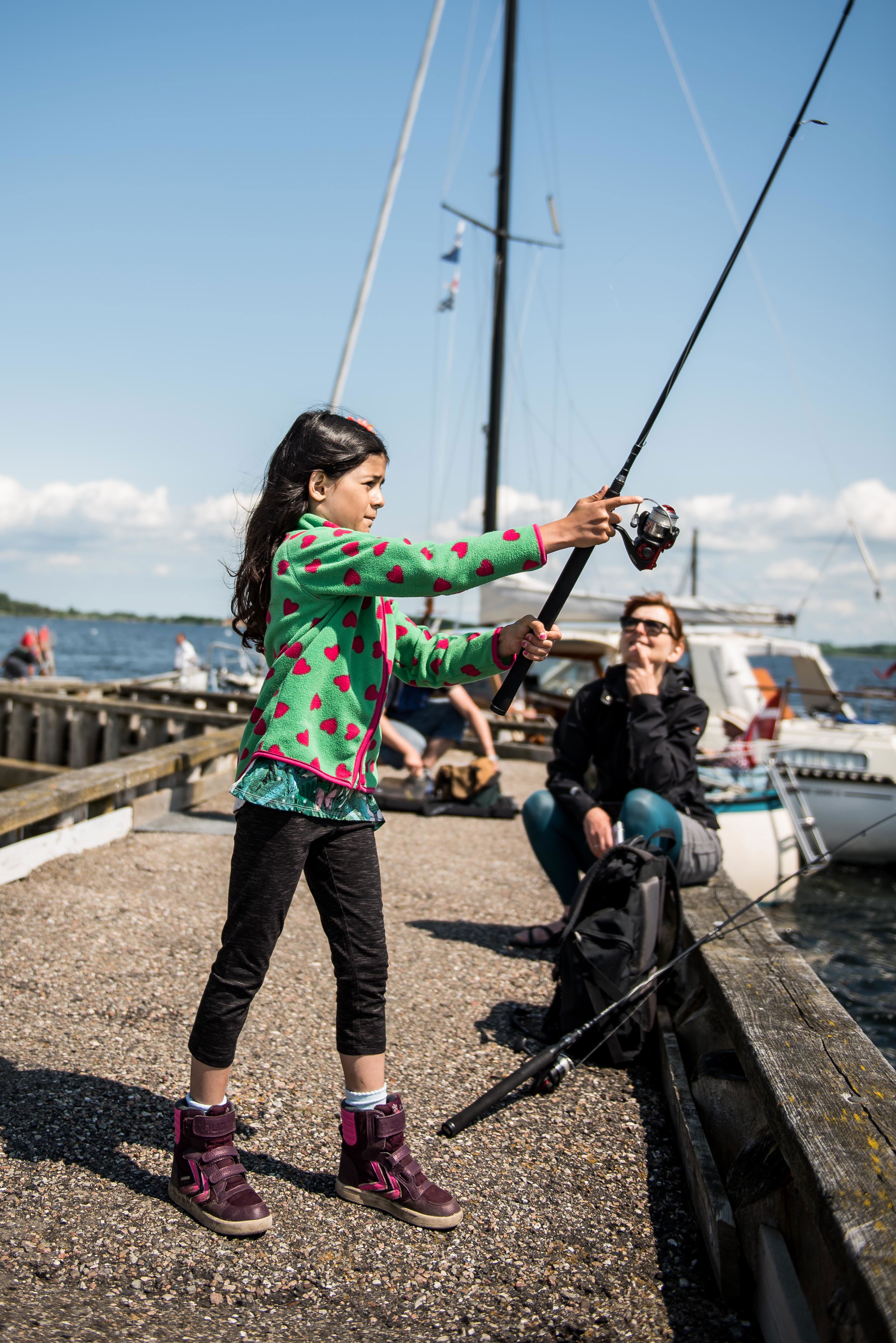 Pige der fisker på mole.