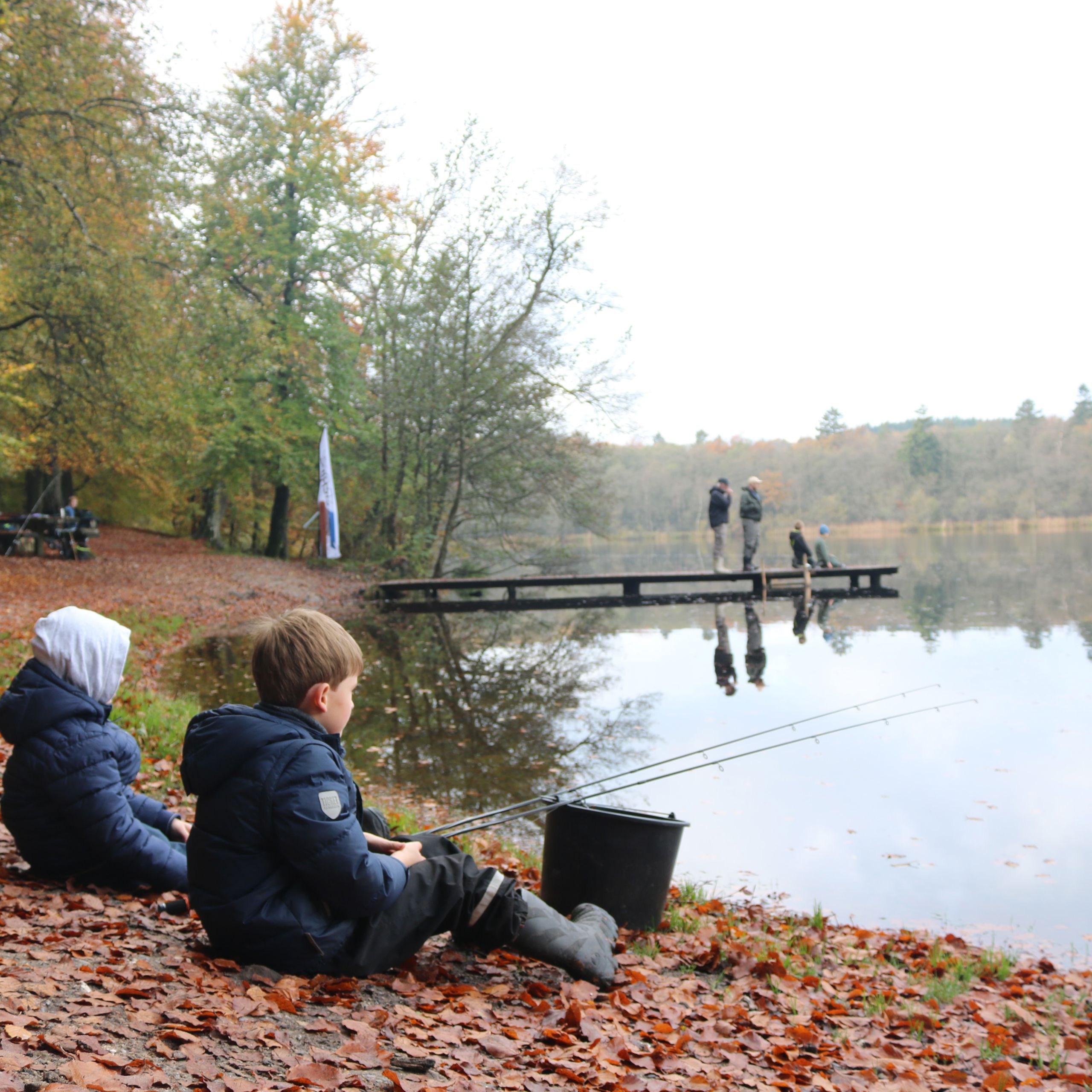 Børn fisker ved sø.