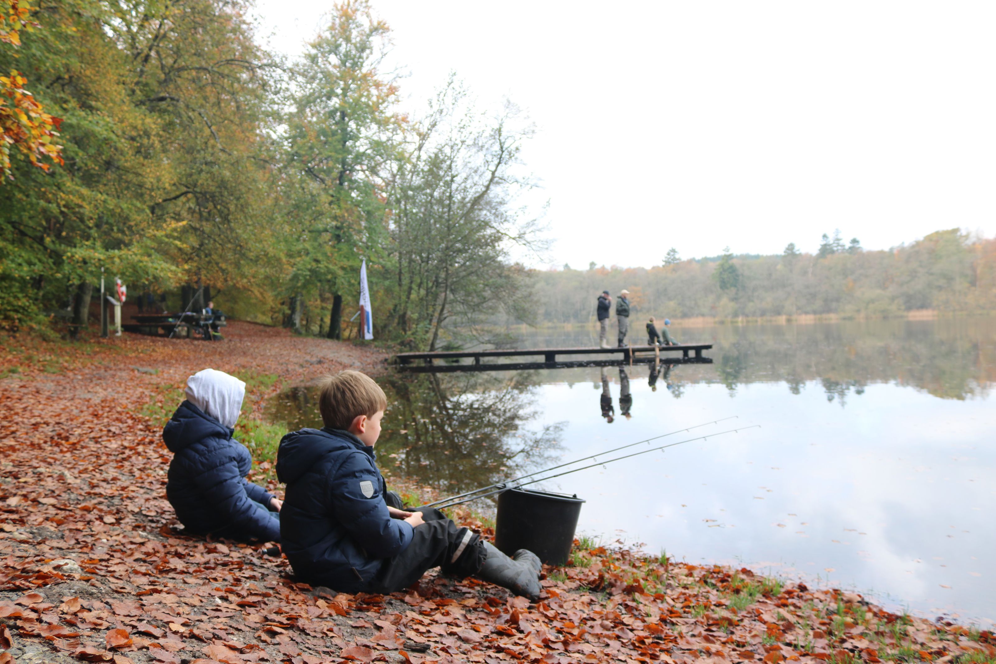 Børn fisker ved sø.