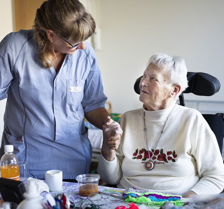 SOSU-hjælper holder ældre dame i hånden.