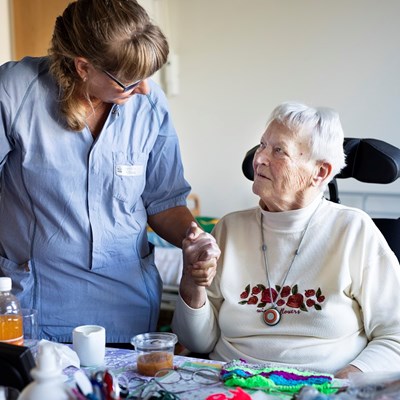 SOSU-hjælper holder ældre dame i hånden.