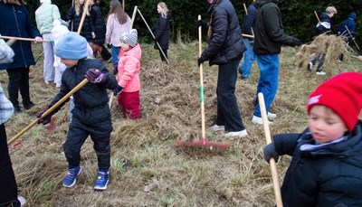 Elever fra Sct. Jørgens skole hjælper til med at fjerne græs fra et areal, hvor urter skal fremmes. 