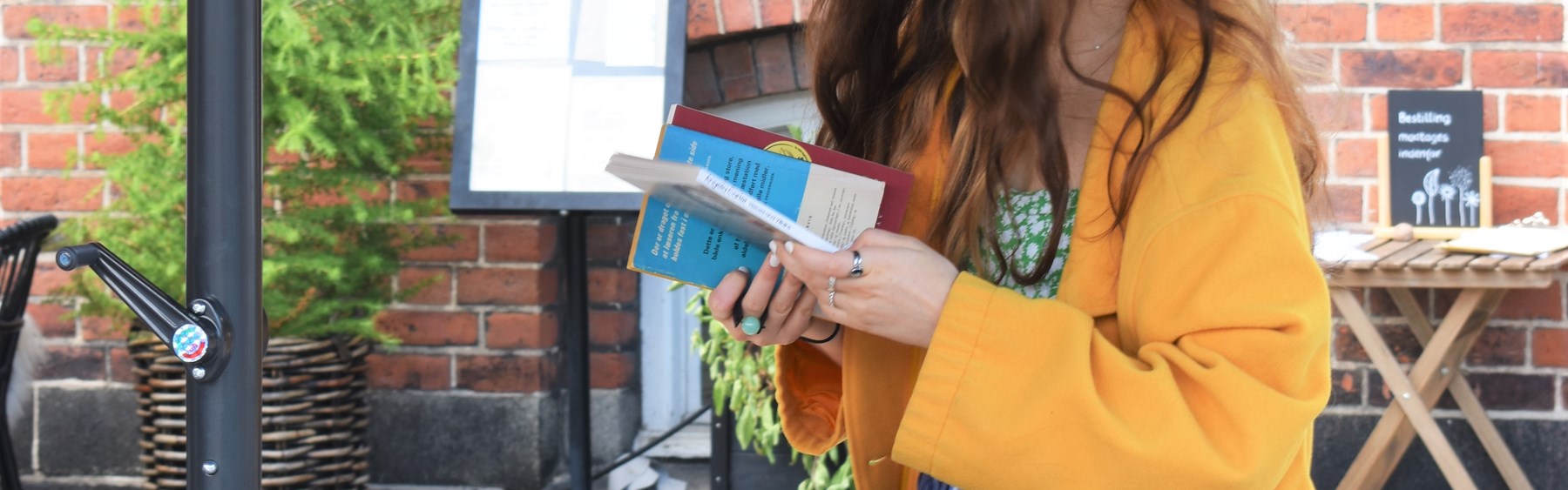 Kvinde i gul jakke kigger på bøger.