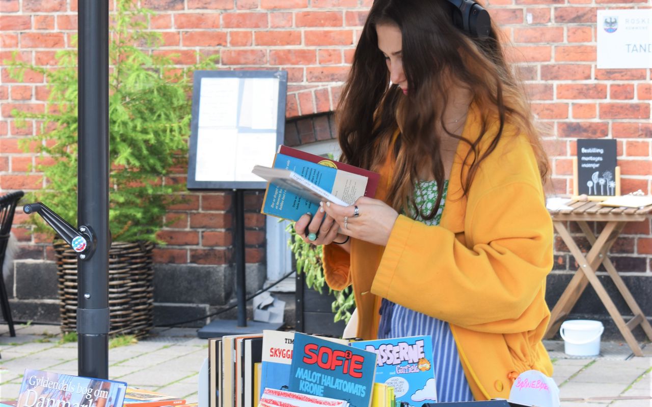 Kvinde i gul jakke kigger på bøger.