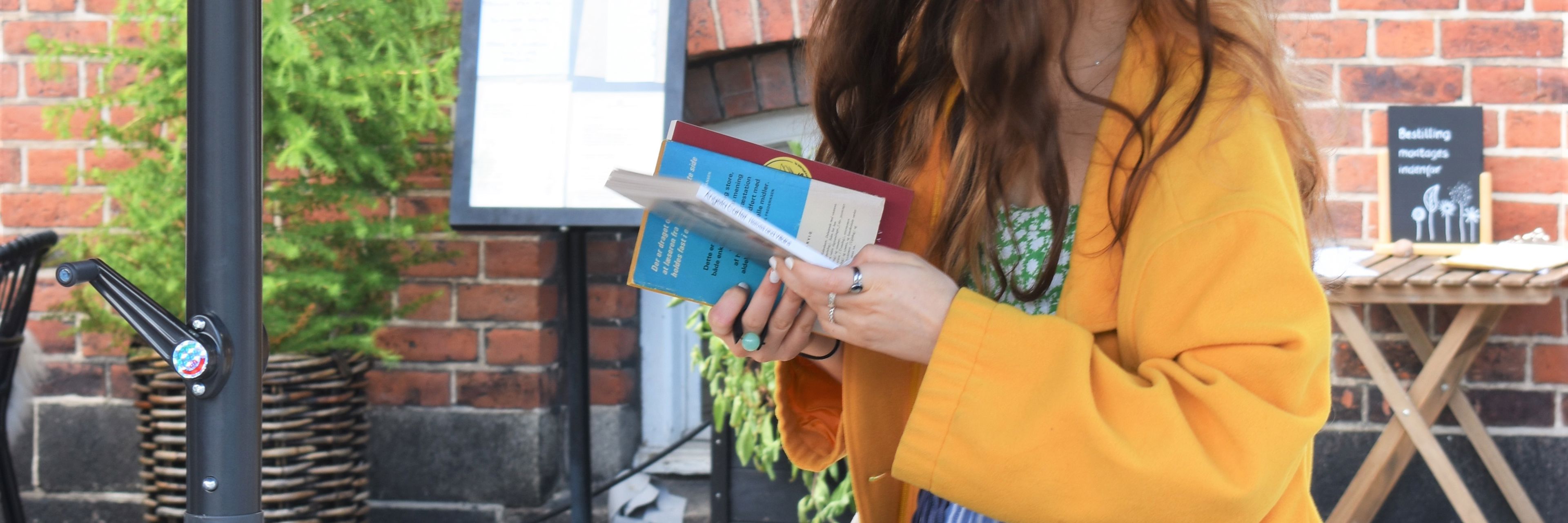 Kvinde i gul jakke kigger på bøger.