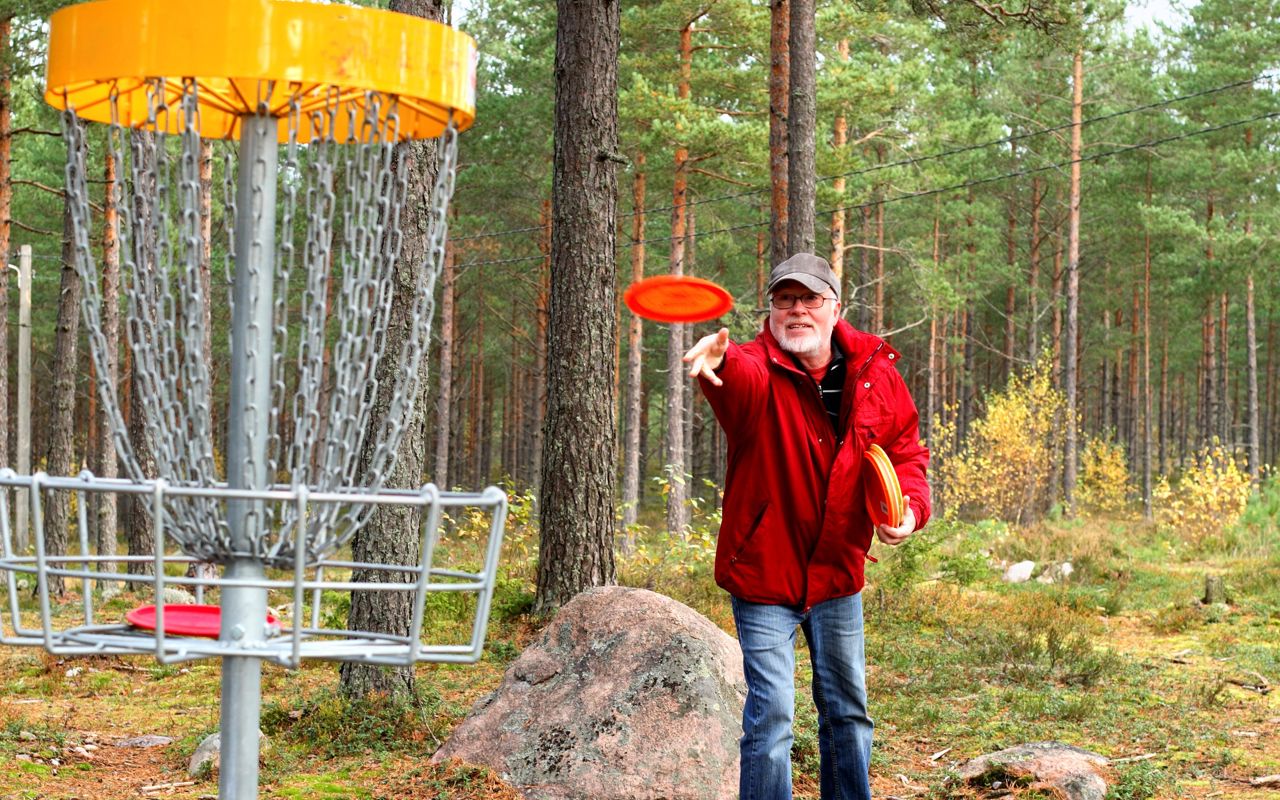 Mand kaster en frisbee. Han spiller discgolf.
