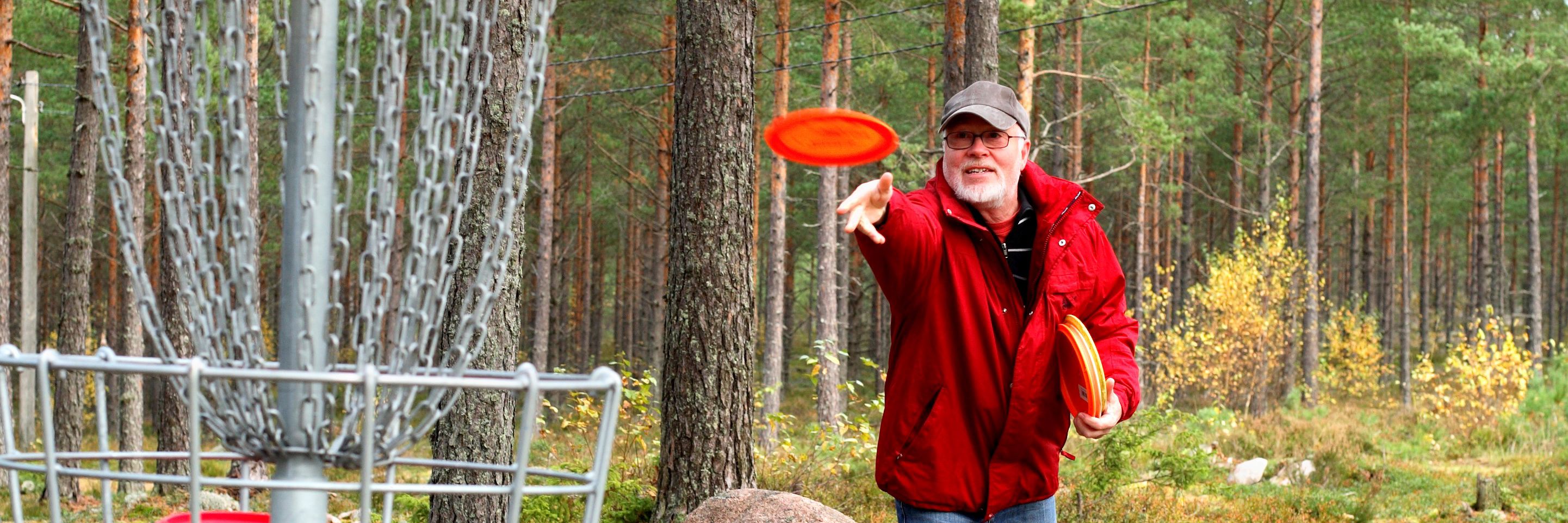 Mand kaster en frisbee. Han spiller discgolf.